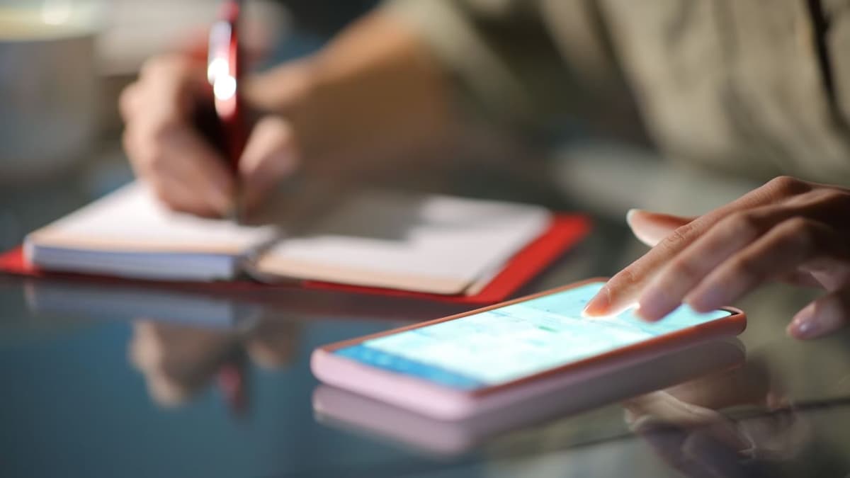 Person using phone calendar app next to physical calendar for planning vehicle shipping dates